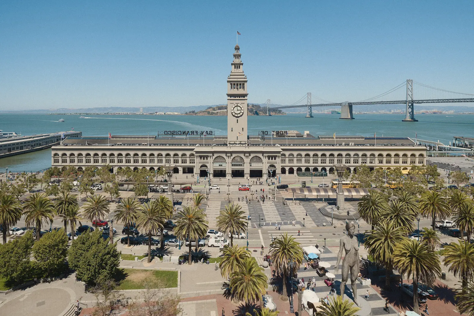 Aerial photo of the Ferry Building clock tower, palm trees and the Bay Bridge